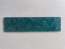 Close-up view of LUX Emerald Green 3x12 glass tile showing its decorative surface